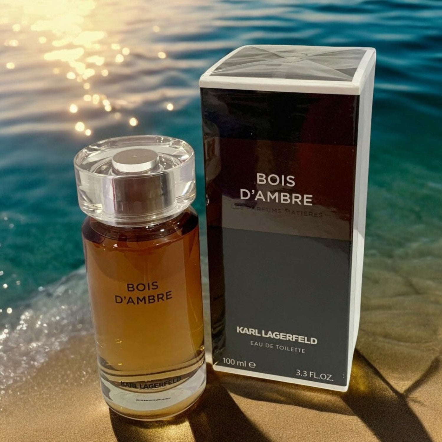 Bois d'Ambre Karl Lagerfeld perfume bottle and packaging on a beach with water in the background