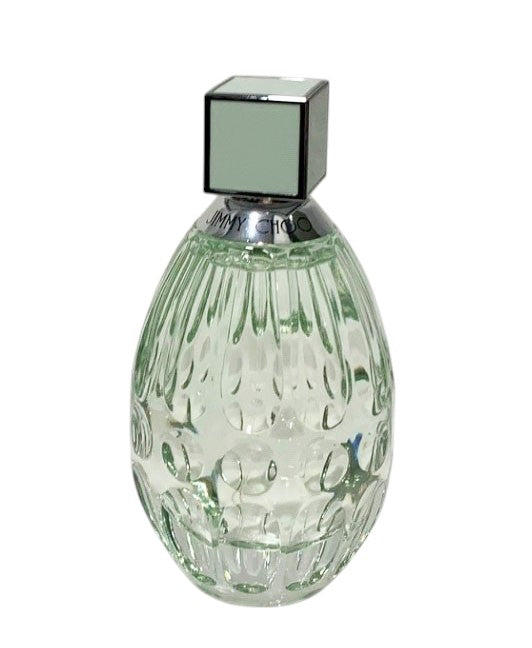 Green glass perfume bottle with silver cap on a white background